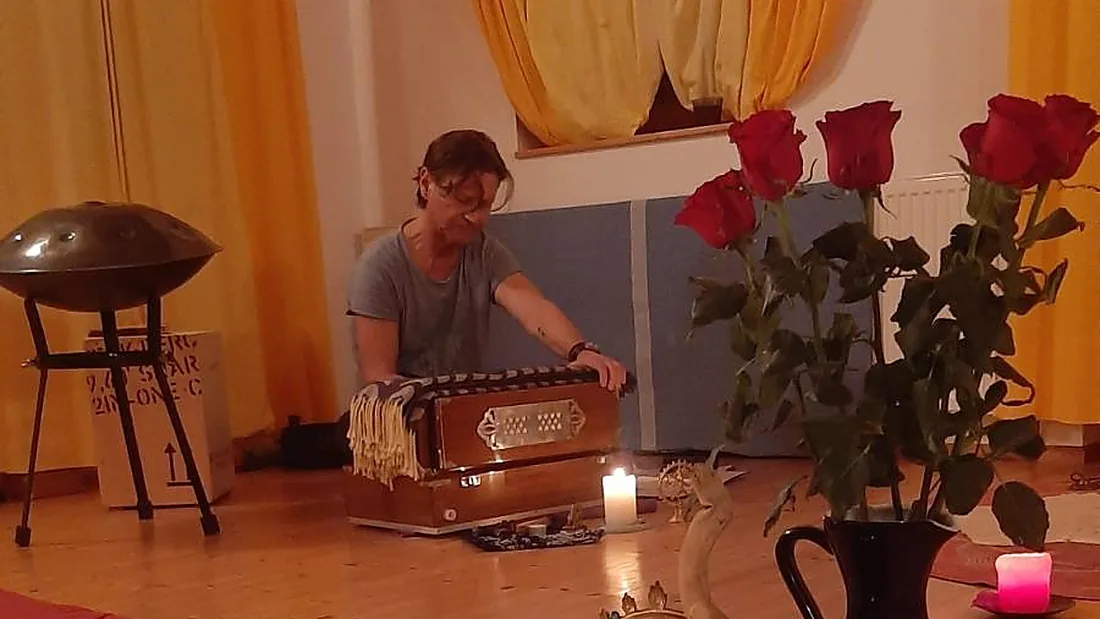 Werner Hauschild spielt Harmonium in einem Raum mit Kerzen, Handpan und roten Rosen